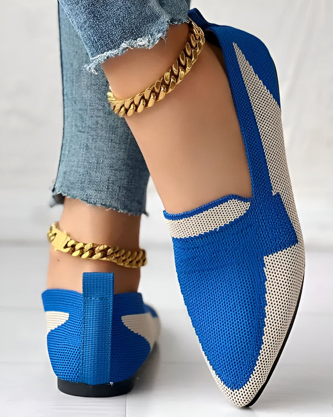 Une femme porte des chaussures bleues et blanches avec un jean et des bijoux.