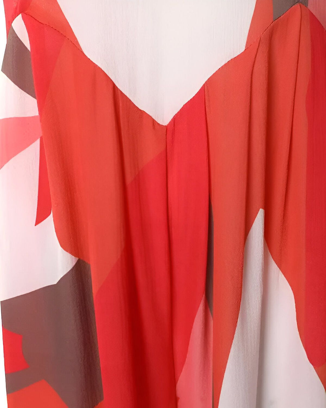 Une image d'une robe en soie rouge et blanche avec un motif géométrique. La robe est sans manches et a une encolure en V.
