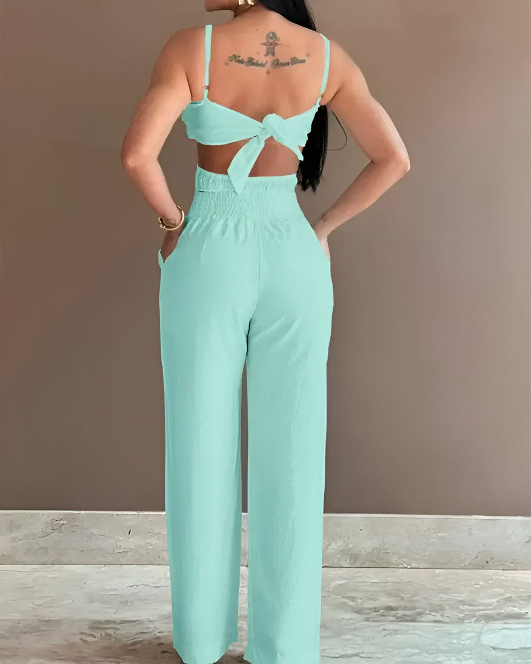Une femme porte une combinaison pantalon vert menthe dos nu.