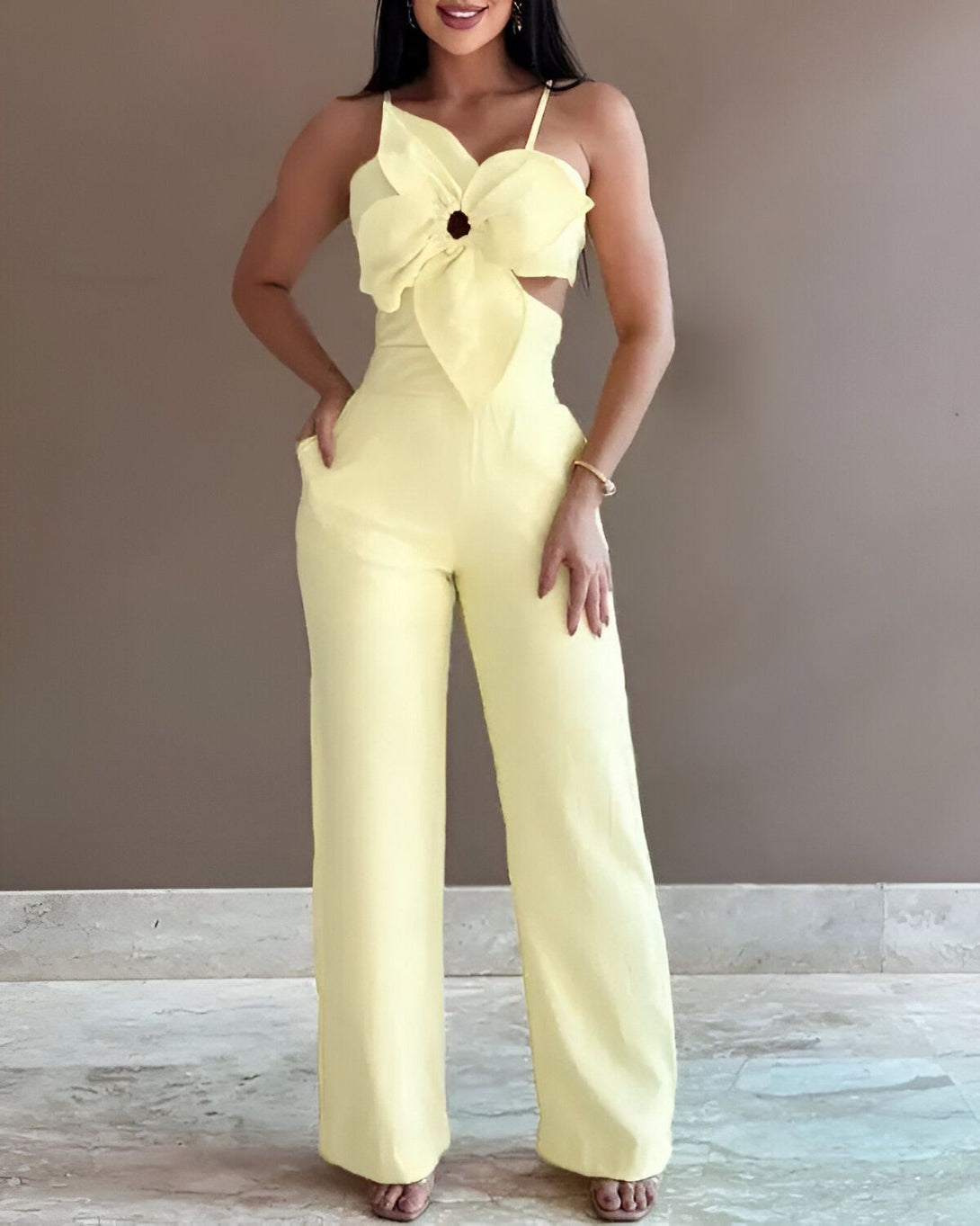 Une femme porte une combinaison pantalon jaune avec un nœud sur le devant.