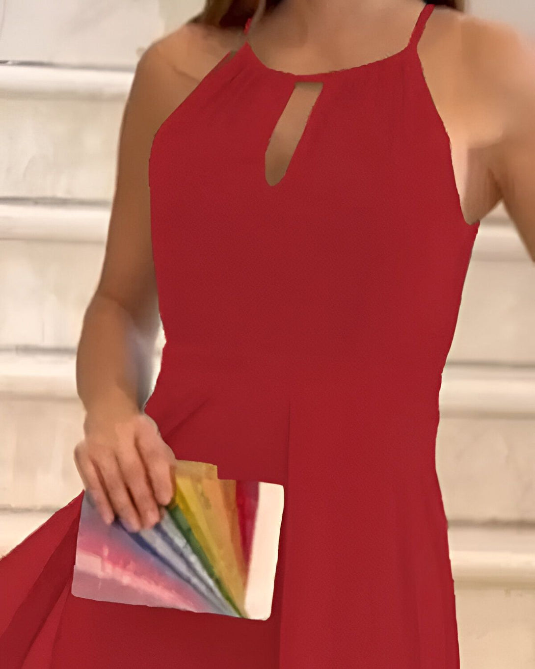 Une femme en robe rouge est debout dans un escalier. Elle tient un nuancier de couleurs à la main.