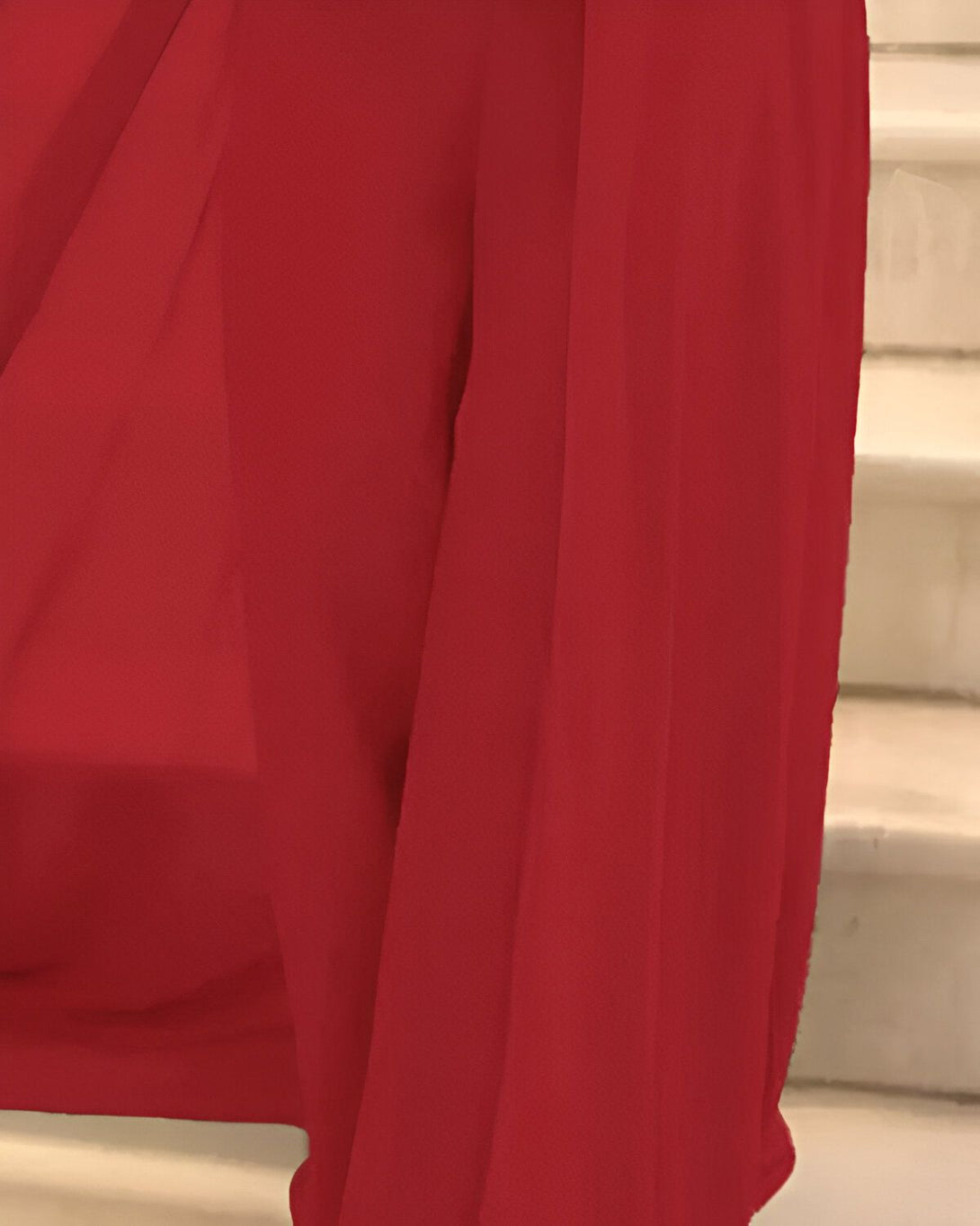 Une image d'une robe de soirée rouge en mousseline de soie. La robe est portée par un mannequin et est photographiée dans un studio.