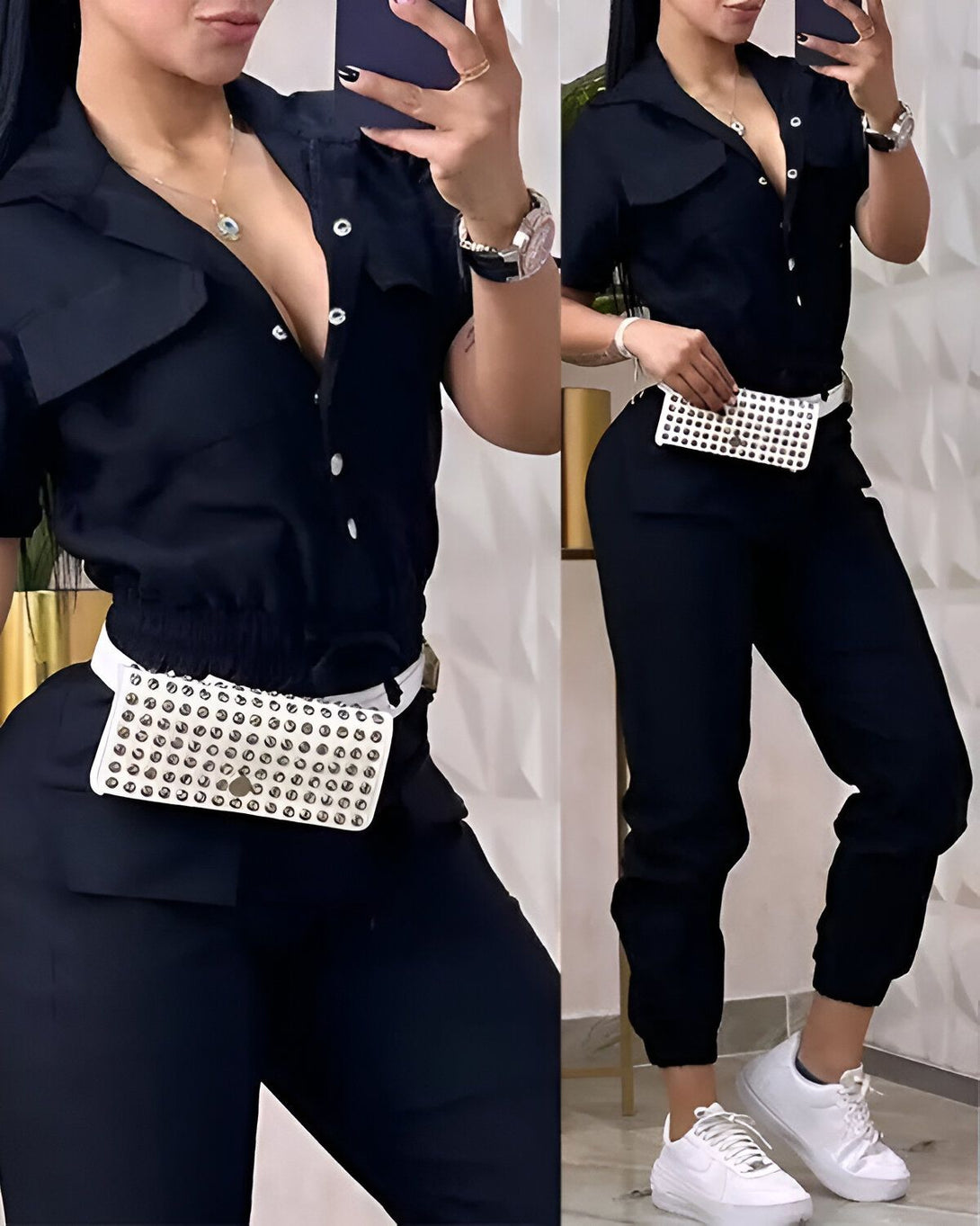 Une femme porte une combinaison noire avec une ceinture blanche cloutée et des baskets blanches. Elle a les cheveux longs et noirs et porte du maquillage. Elle est debout dans un champ de fleurs sauvages.