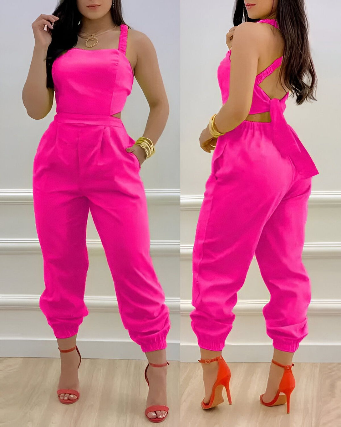 Une femme porte une combinaison pantalon rose fuchsia. La combinaison est près du corps et a un décolleté en cœur. Elle est ouverte dans le dos et nouée au cou. La femme porte des sandales à talons rouges et des bijoux dorés.