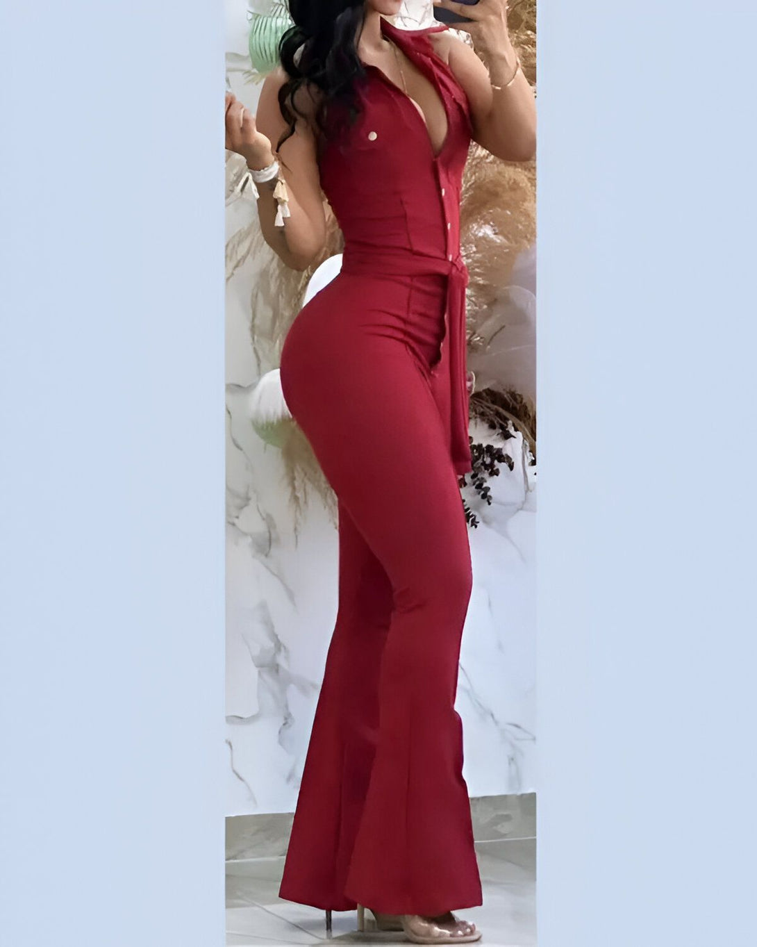 Une femme porte une combinaison-pantalon rouge. La combinaison est cintrée à la taille et évasée au niveau des jambes. Elle est décolletée et possède un col montant. La femme est vue de dos.