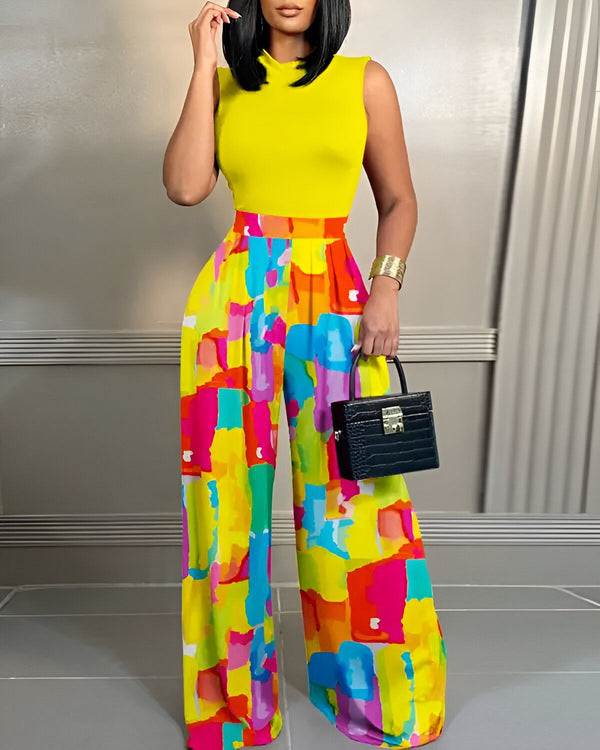 Une femme porte un pantalon large et coloré avec un haut jaune. Elle porte également un sac à main noir et des talons hauts.