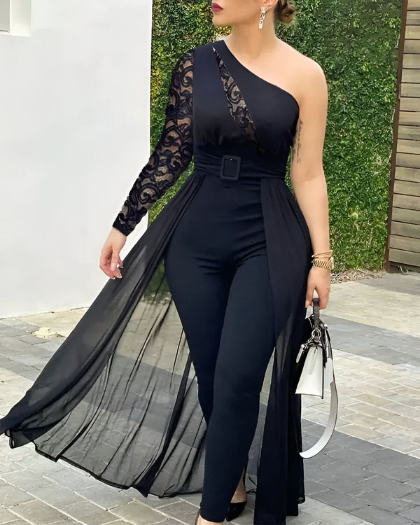 Une femme porte une combinaison noire avec une manche en dentelle et un pantalon évasé. Elle porte également une ceinture noire et des talons noirs.
