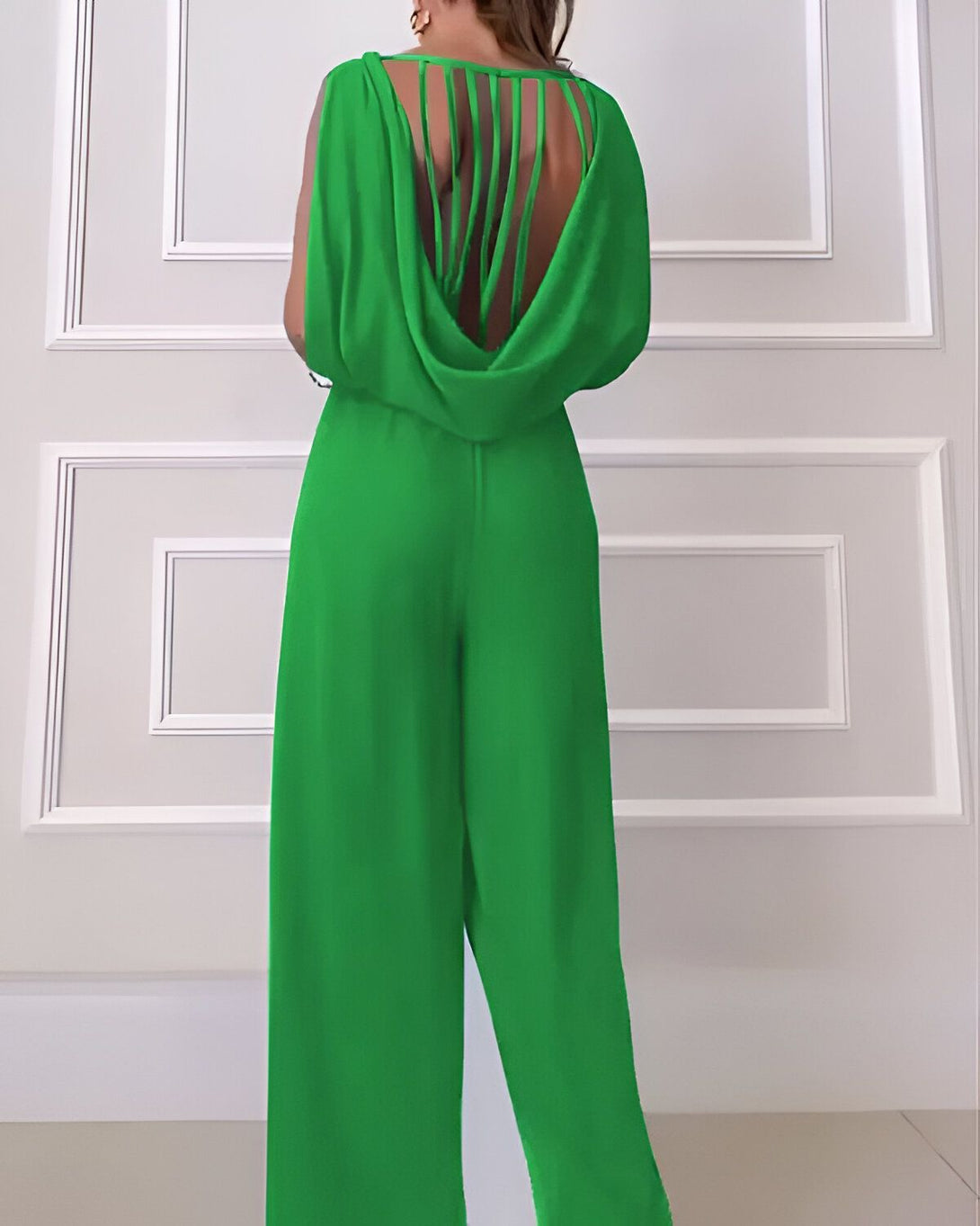 Une femme porte une combinaison pantalon verte dos nu.