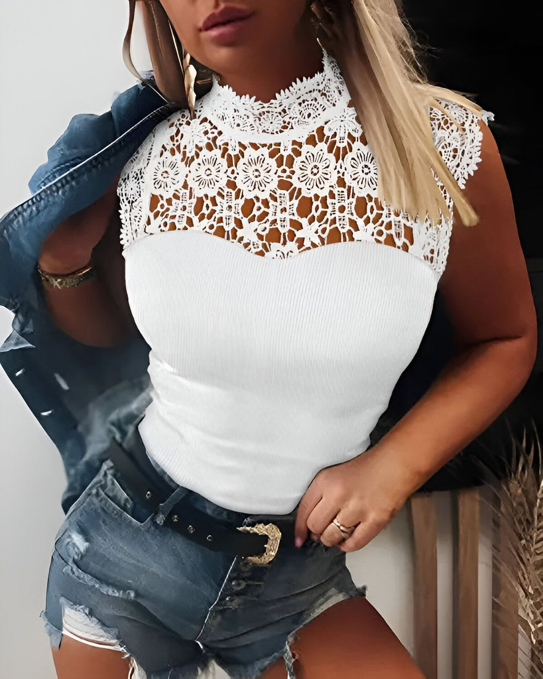 Une femme porte un chemisier blanc avec un col en dentelle. Elle porte également un jean bleu et une veste en jean.