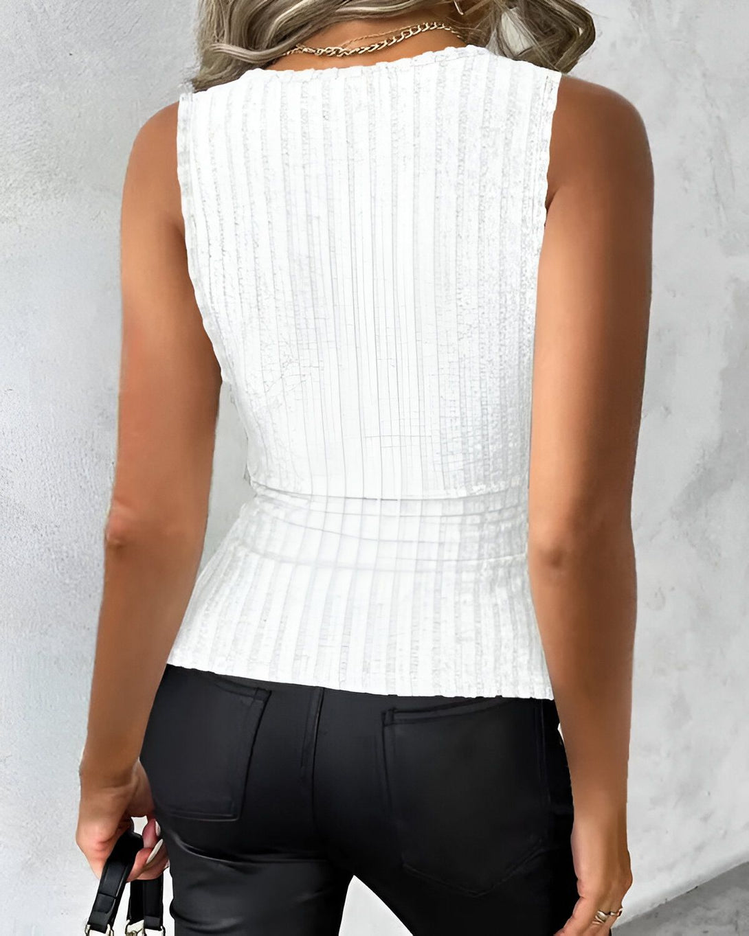 Une femme porte un débardeur côtelé blanc et un pantalon noir.
