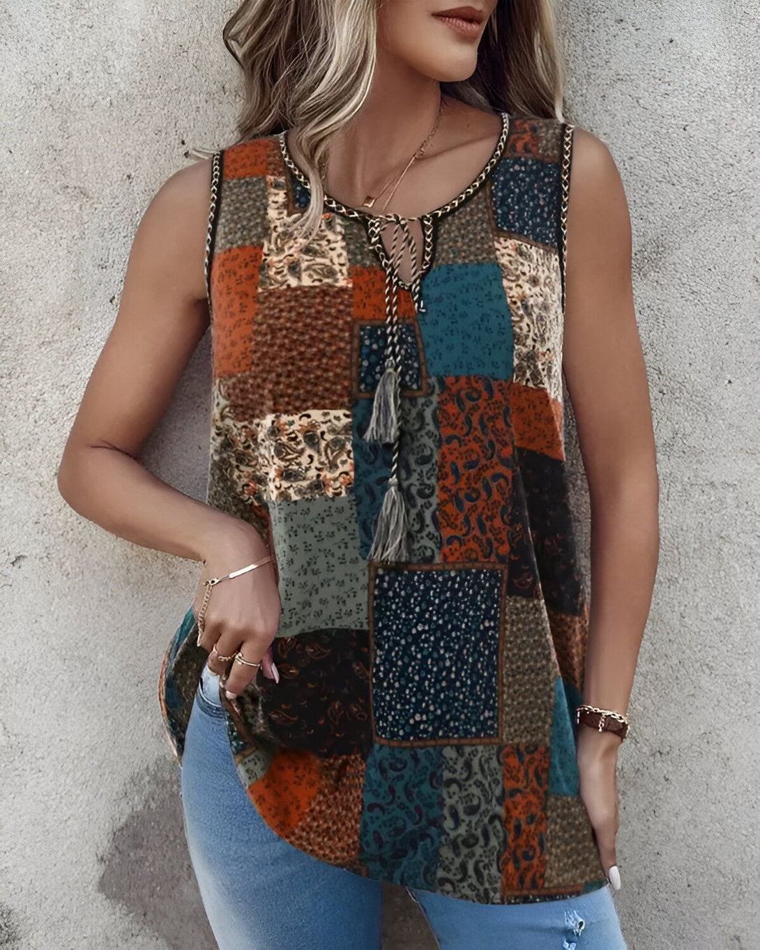 Une femme porte un débardeur marron et bleu à motifs cachemire et paisley. Elle est également porte un jean bleu et des talons hauts marrons.