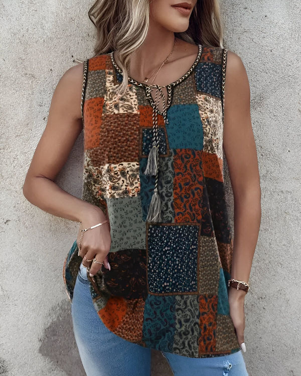 Une femme porte un débardeur marron et bleu à motifs cachemire et paisley. Elle est également porte un jean bleu et des talons hauts marrons.