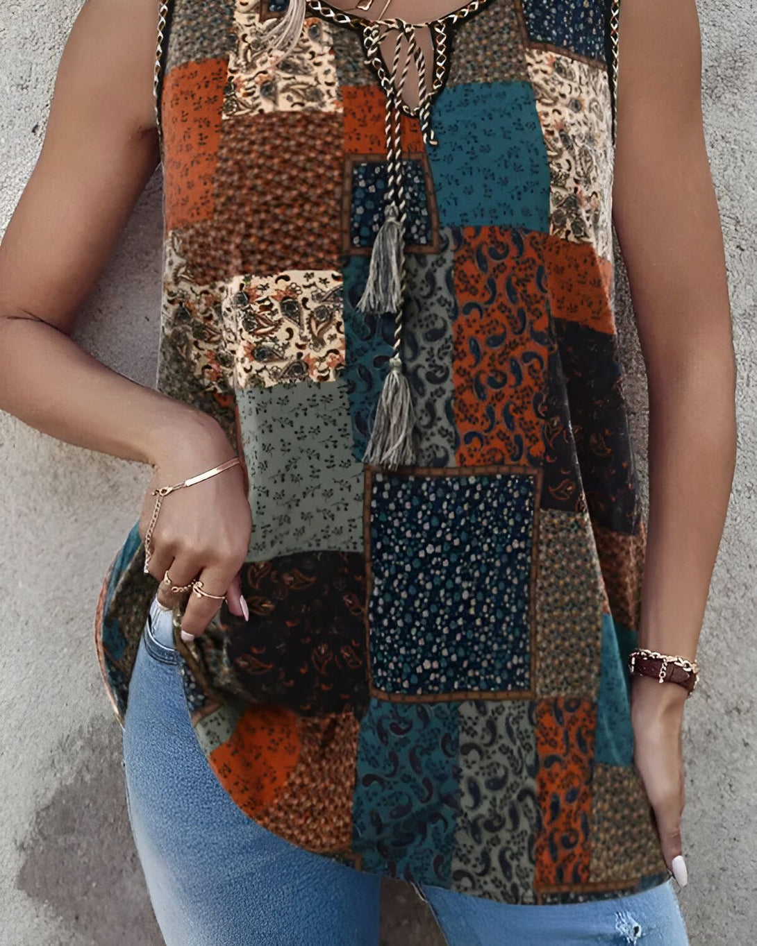 Une femme porte un haut sans manches à motifs cachemire et un jean bleu.