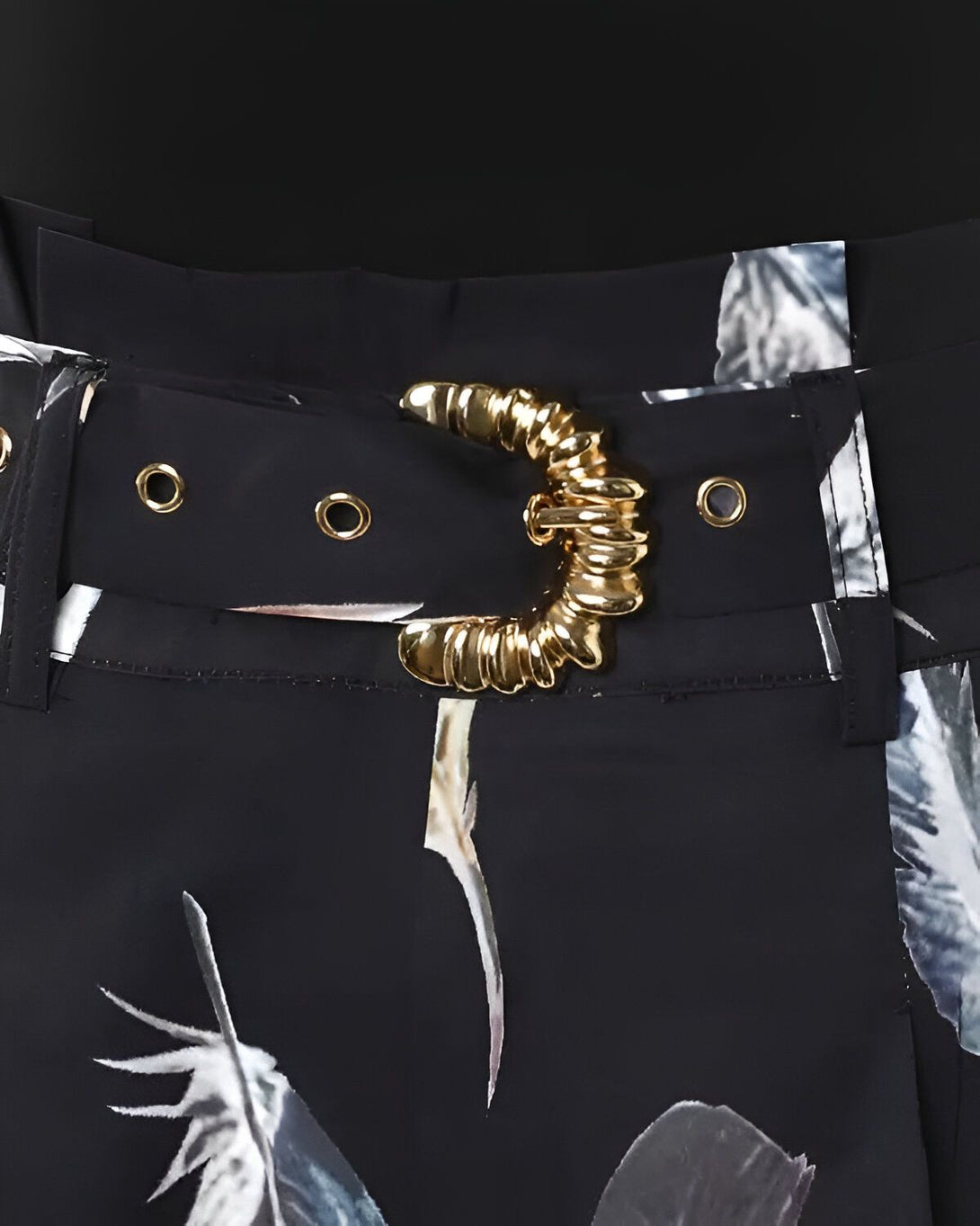 Une image d'une ceinture noire avec une boucle dorée. La ceinture est ornée d'un motif floral.