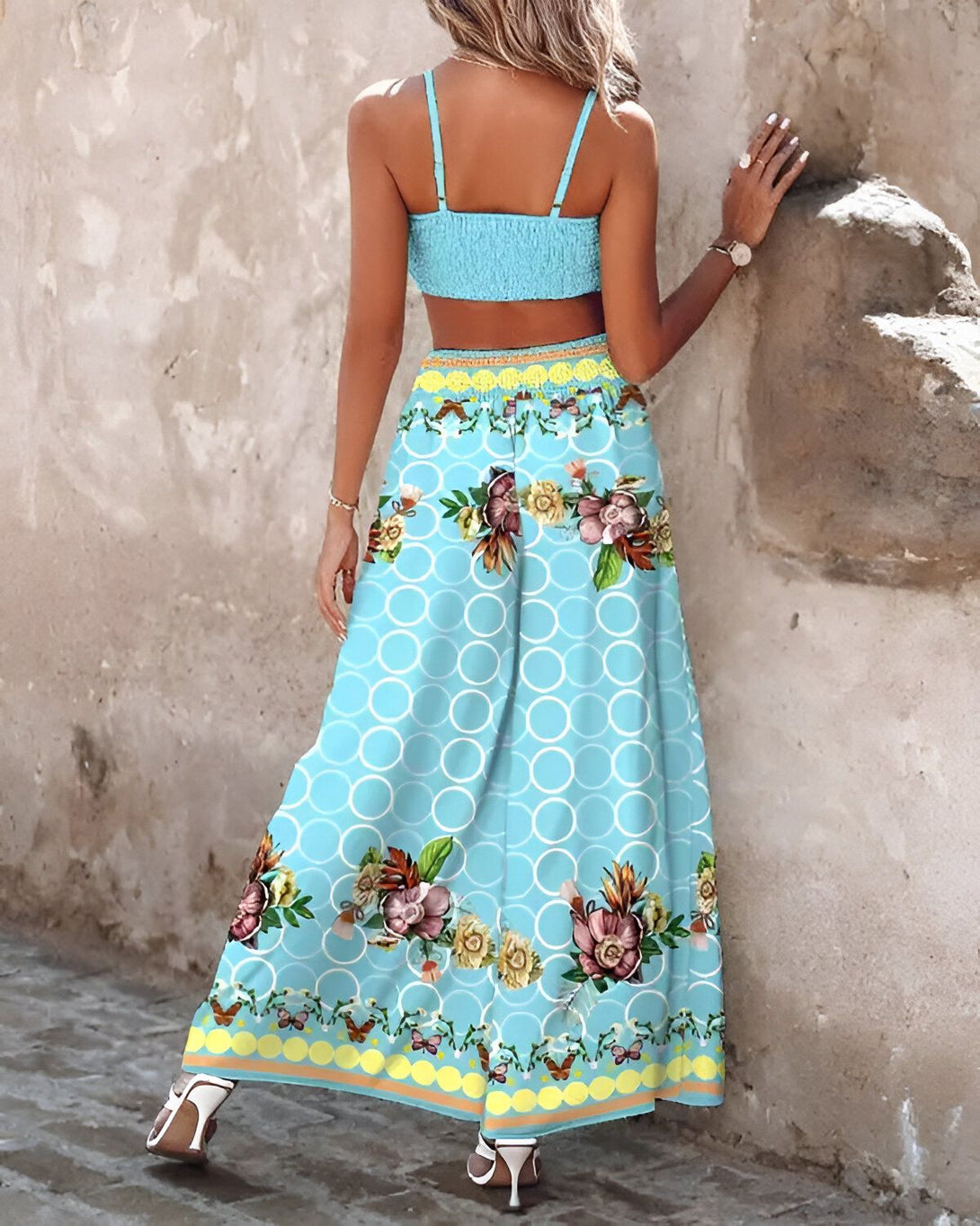 Une femme porte un haut court bleu clair et un pantalon large bleu à motifs floraux.
