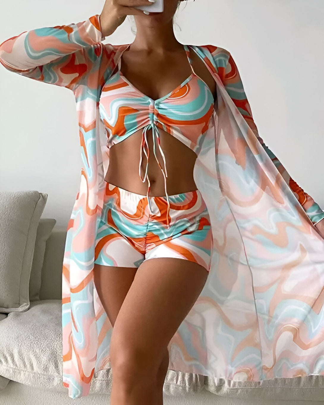 Une femme porte un ensemble de trois pièces de couleur orange et bleu. Il est composé d'un short, d'un haut et d'une veste transparente.