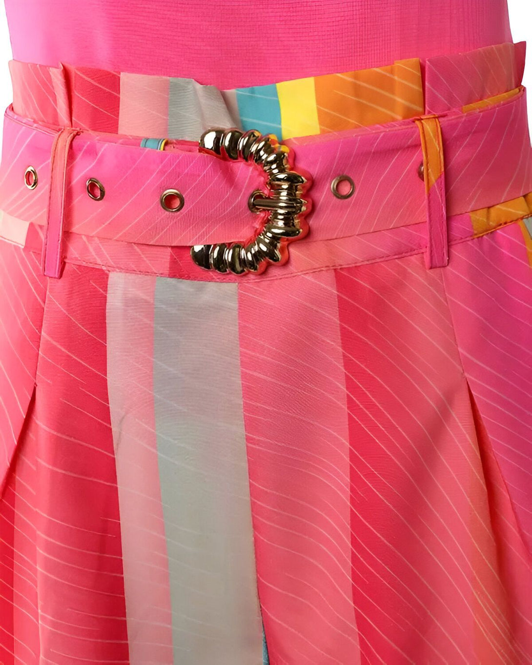 Ceinture en métal doré sur un pantalon plissé rose et coloré.