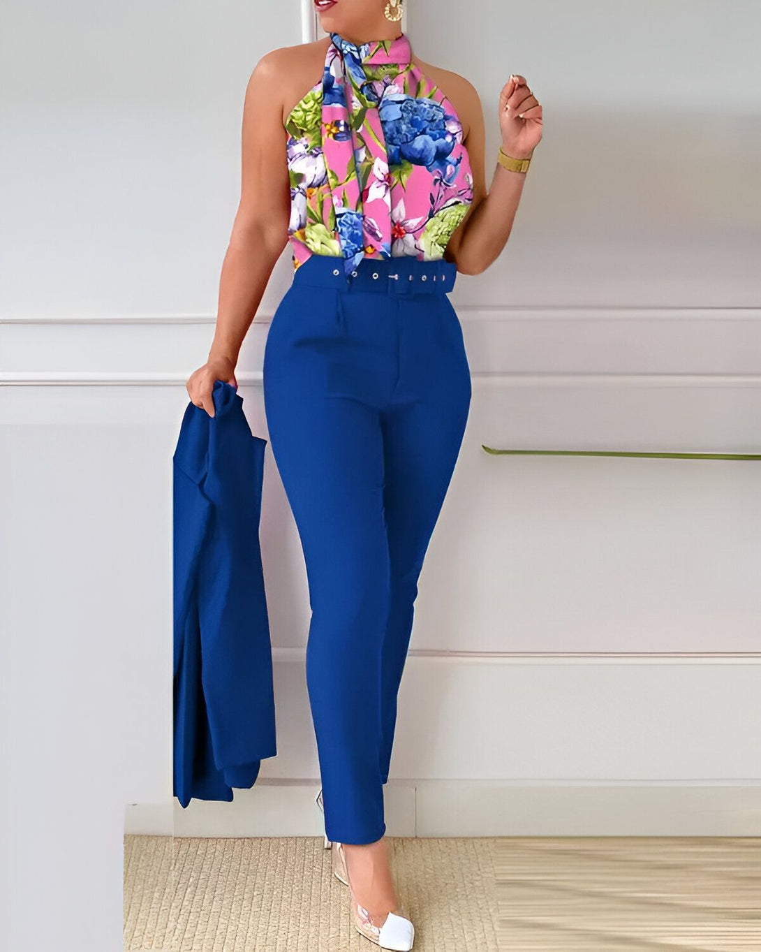 Une femme porte un tailleur pantalon bleu avec un haut à fleurs et un blazer bleu.