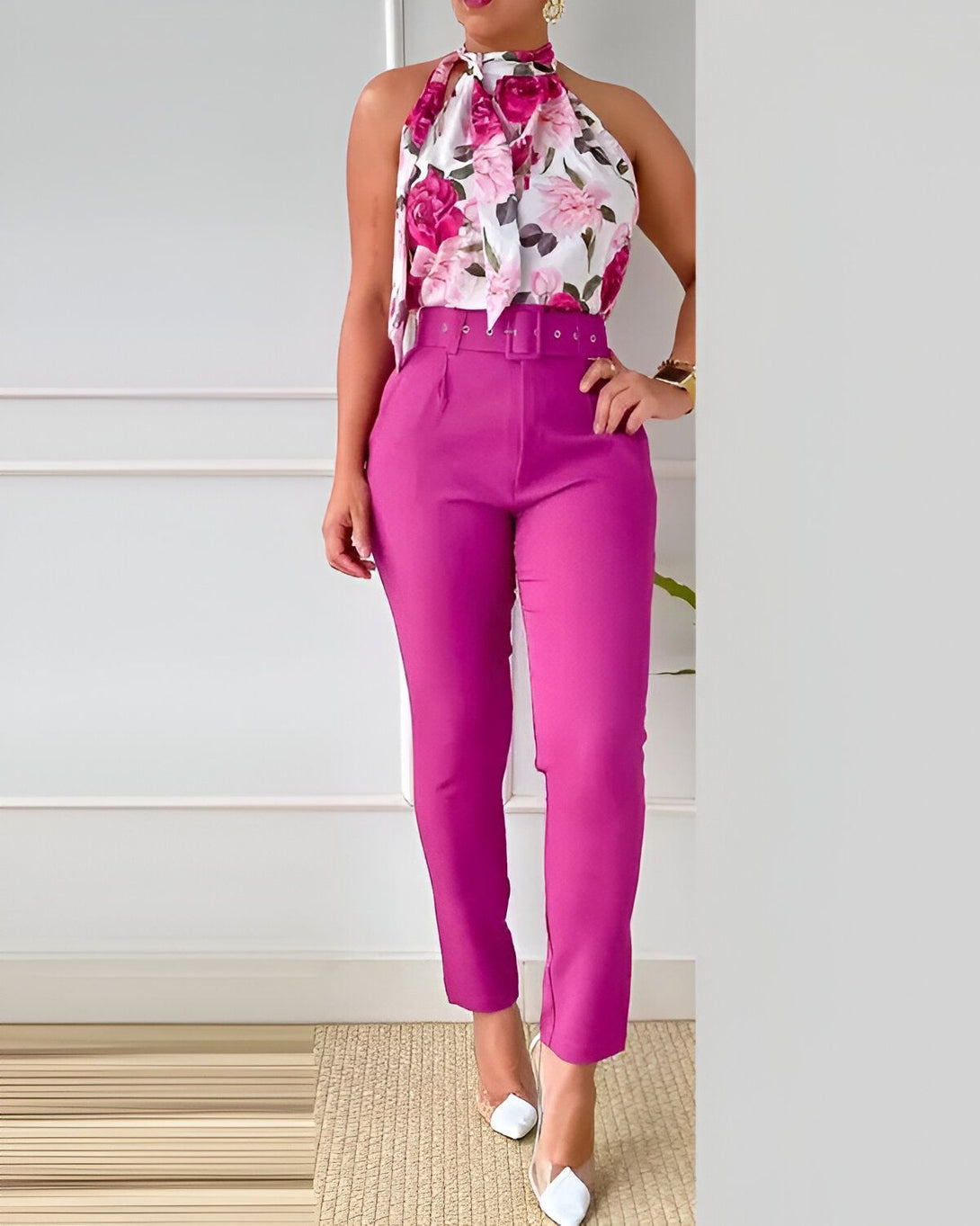 Une femme porte un pantalon rose fuchsia et un haut à motif floral avec un nœud dans le cou.