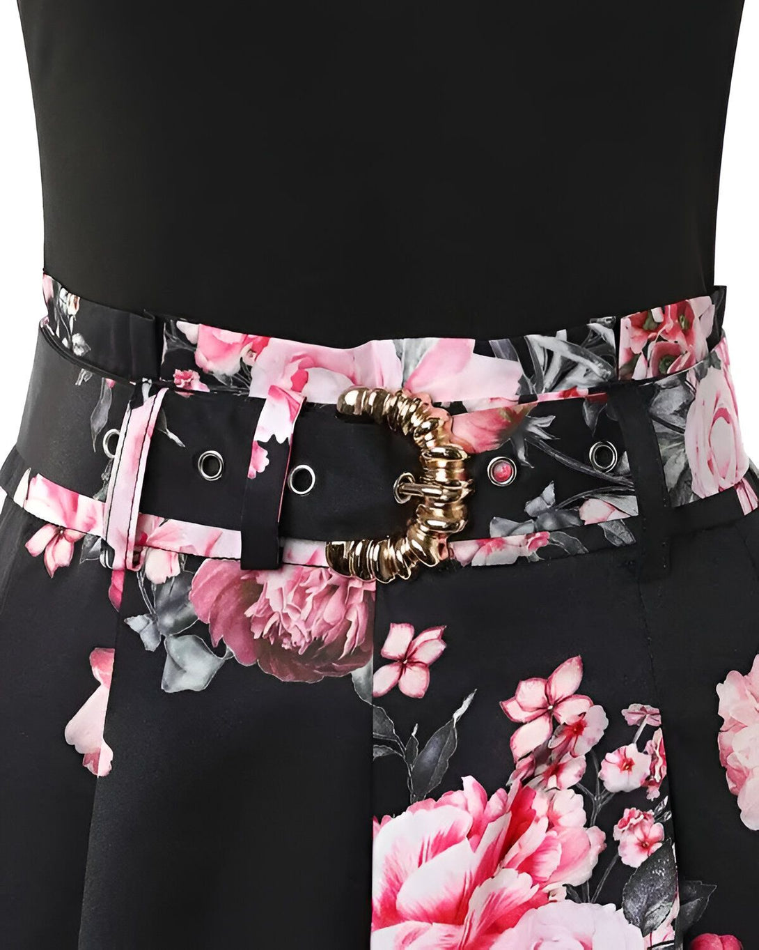 Une image d'une ceinture noire avec une boucle dorée sur une jupe noire à motifs floraux roses.