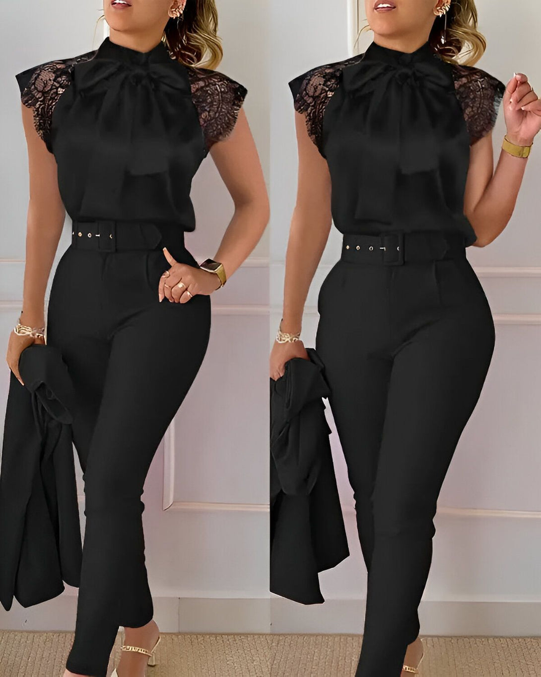 Une femme porte un chemisier noir en dentelle et un pantalon noir. Elle est ceinturée d'une ceinture noire et porte des escarpins noirs. Elle a les cheveux longs et noirs et porte un maquillage léger. Elle se tient debout dans une position confiante.