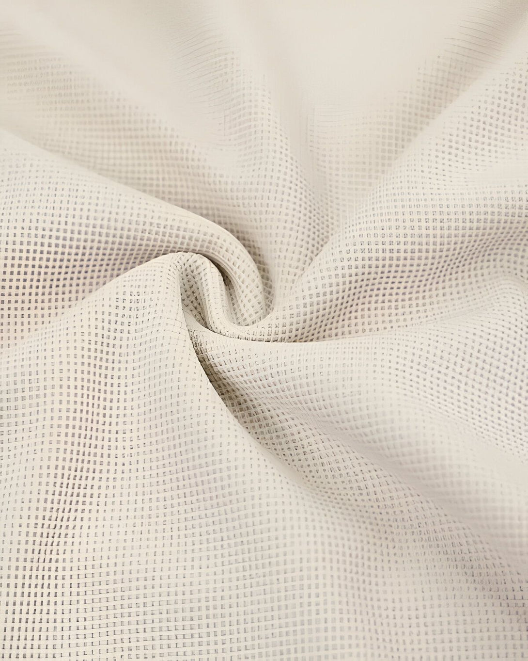 Une image de tissu beige avec un motif de petits carrés. Le tissu est froissé et on peut voir les fils qui le composent.