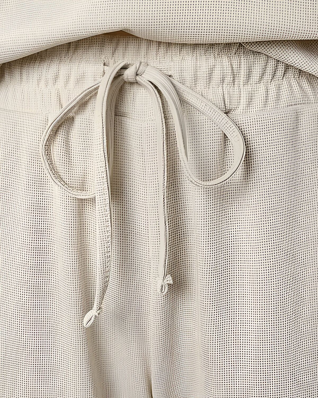 Une image d'un pantalon beige avec un cordon de serrage à la taille.