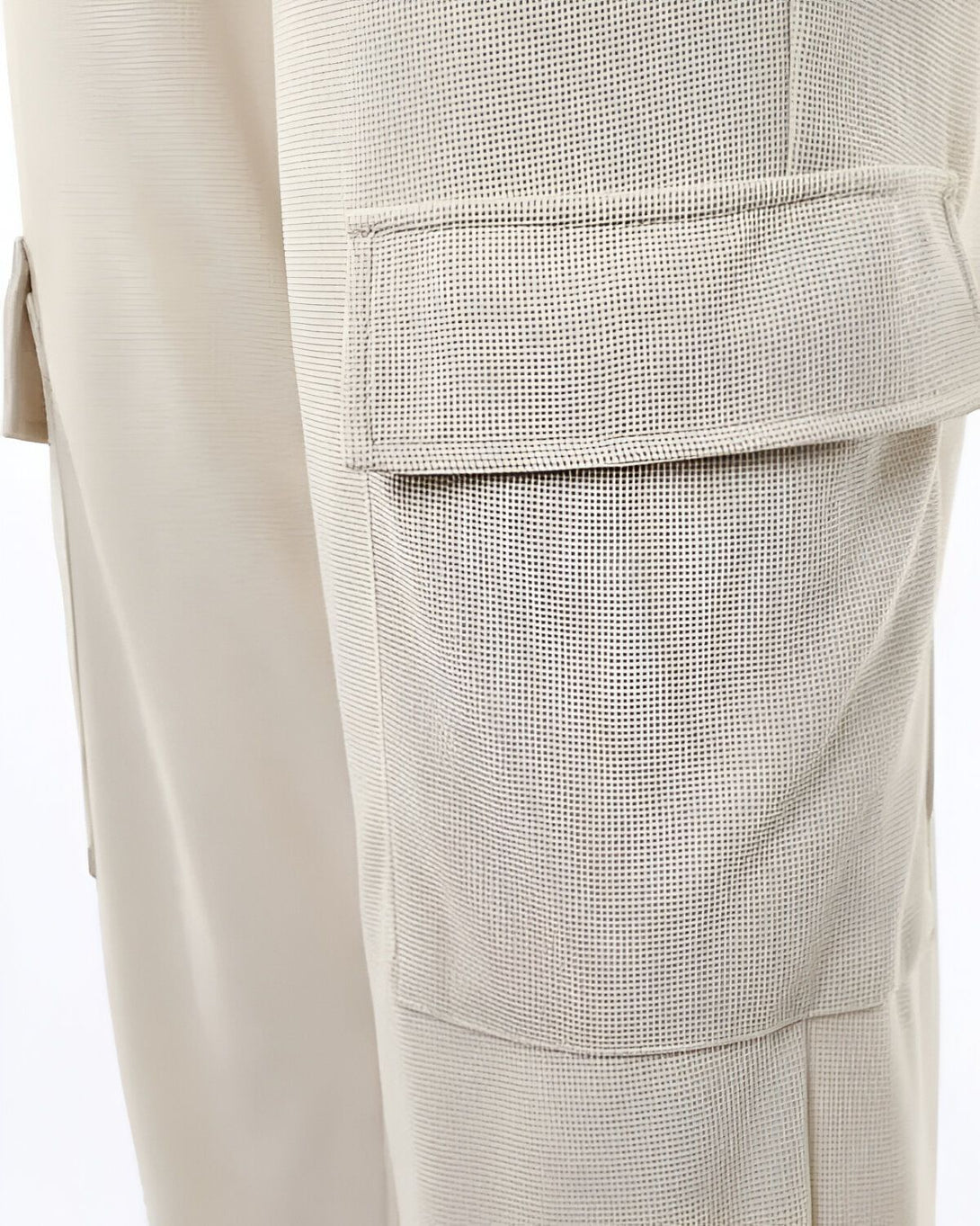 Le pantalon cargo beige est doté d'une poche cargo sur le côté de la jambe. La poche est en filet et de couleur beige.