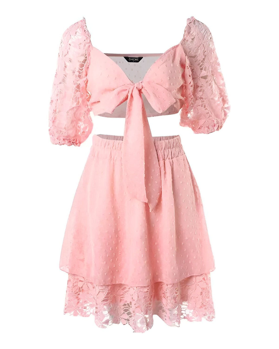 Un ensemble deux pièces rose composé d'un crop top à manches bouffantes et d'une jupe courte évasée. Le crop top est en dentelle avec un nœud papillon à l'avant. La jupe est en mousseline de soie avec un volant en dentelle au bas.