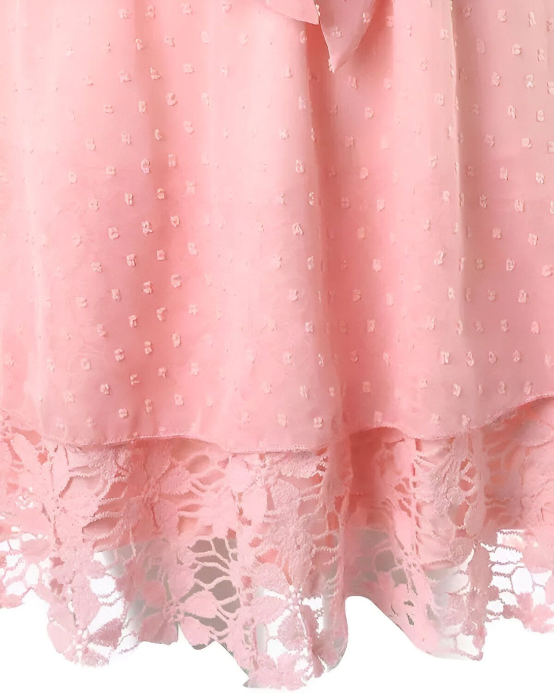 Une robe rose en mousseline de soie avec des pois blancs et un nœud à la taille. La robe est doublée de dentelle rose.