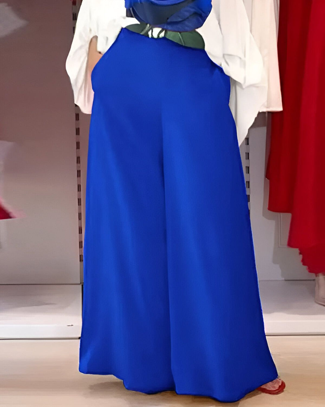 Une femme porte un pantalon bleu large et une blouse blanche.