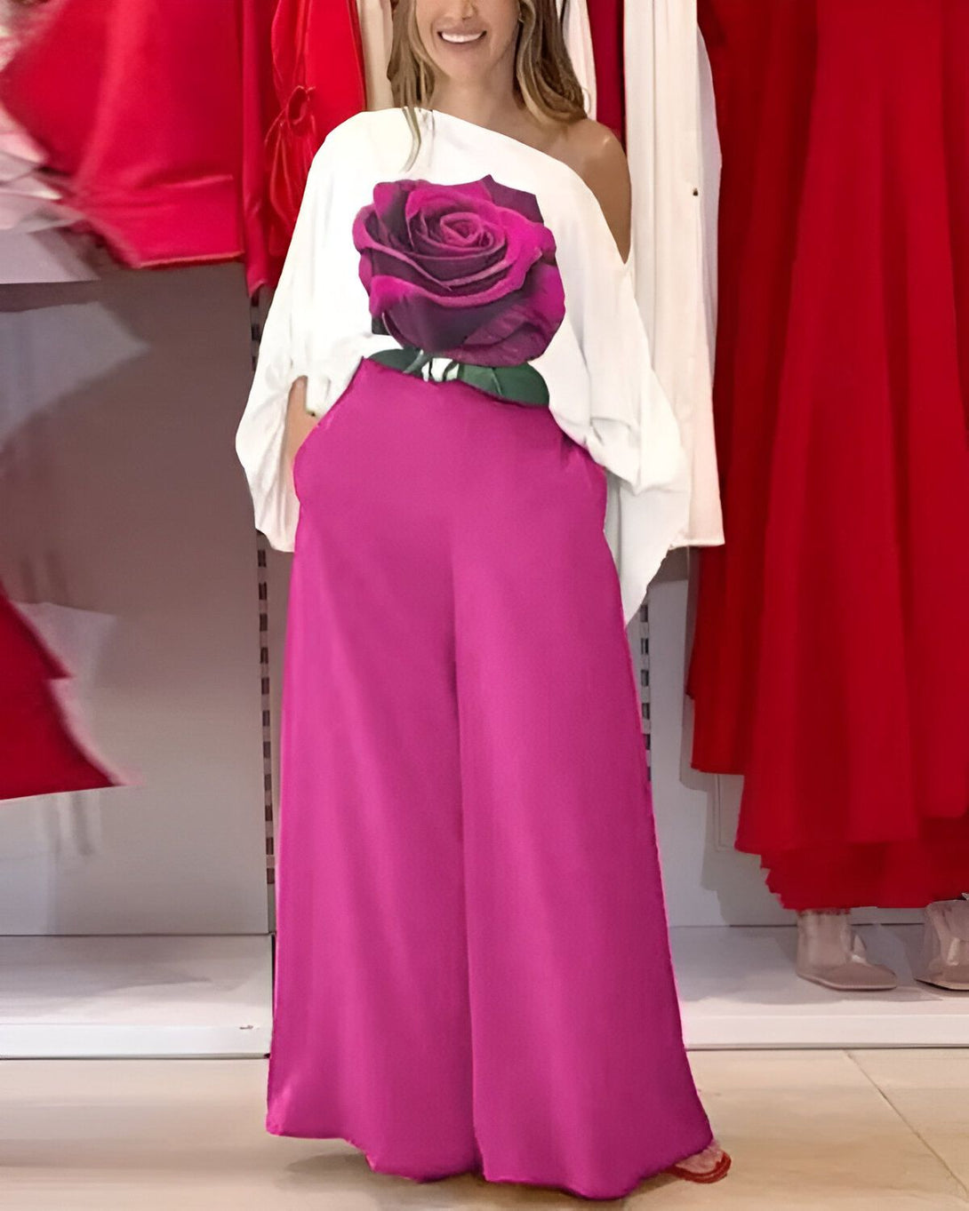 Une femme porte un chemisier blanc avec une image de rose rose et un pantalon rose.