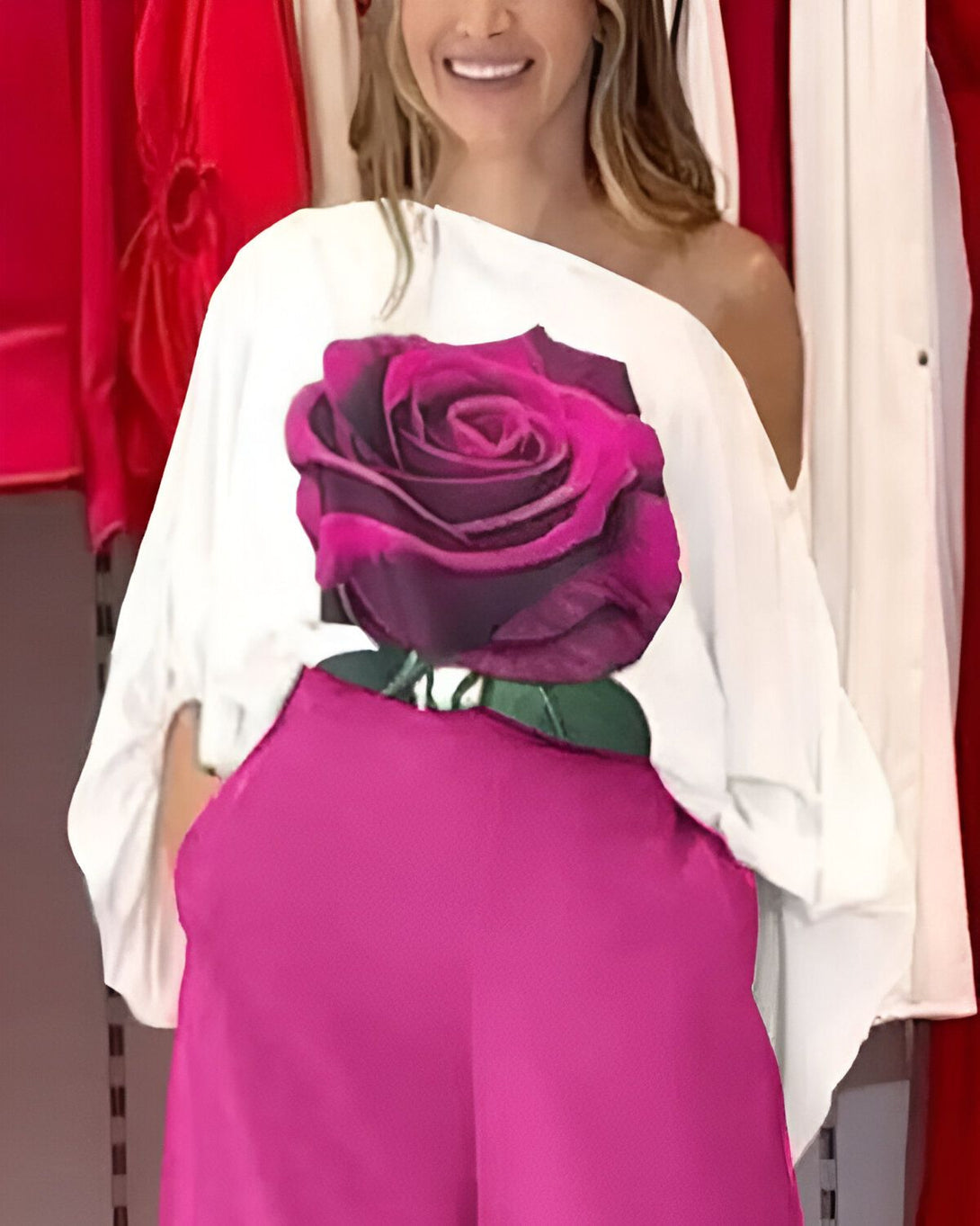 Une femme porte un chemisier blanc avec une image d'une rose rose. Elle porte aussi un pantalon rose.