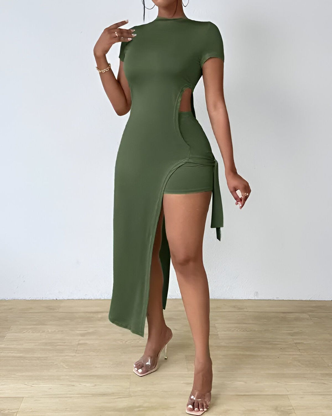 Une femme porte une robe longue verte fendue sur le côté avec un short intégré. Elle porte également des talons transparents.