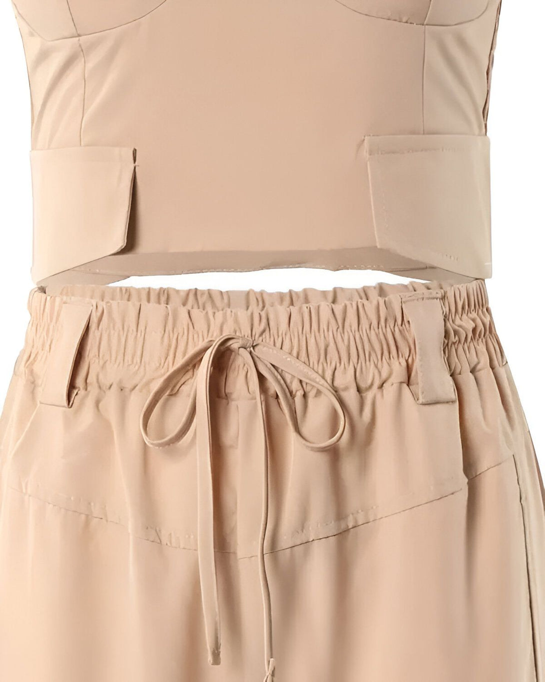 Un ensemble de couleur beige composé d'un crop top et d'un pantalon taille haute. Le crop top est court et possède des poches sur le devant. Le pantalon est long et possède une ceinture à nouer à la taille.