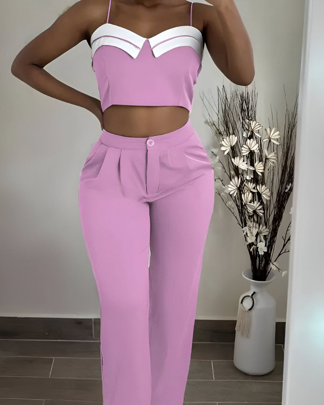 Une femme porte un ensemble pantalon et haut rose. Le haut est court et le pantalon est taille haute.