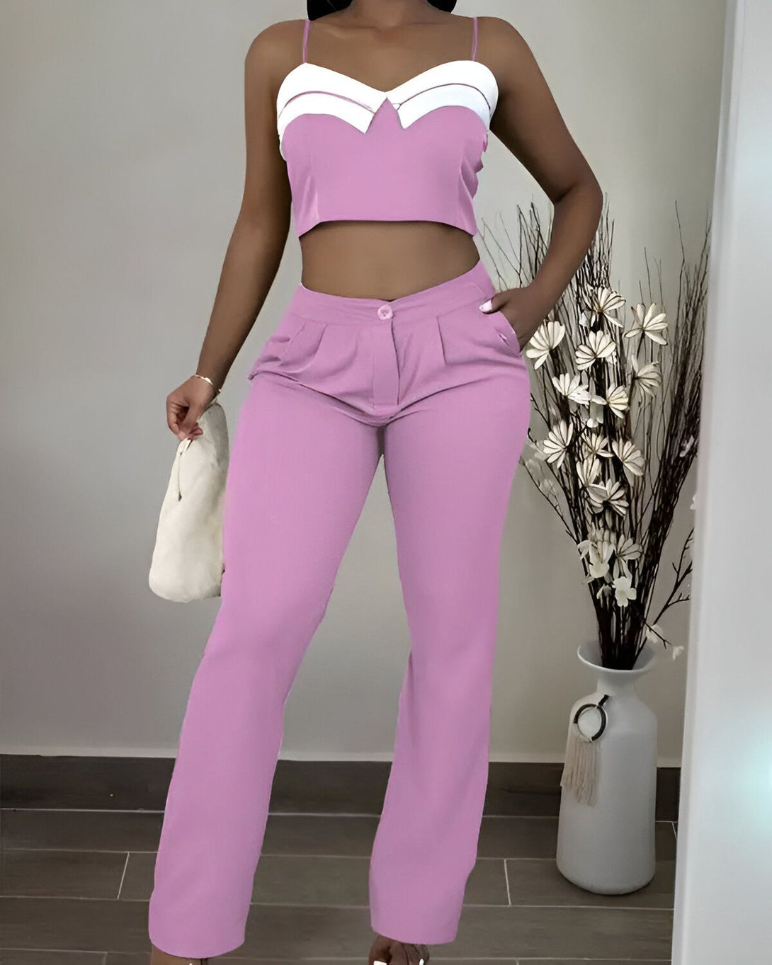 Une femme porte un ensemble pantalon et haut rose. Le haut est court et le pantalon est taille haute et évasé.