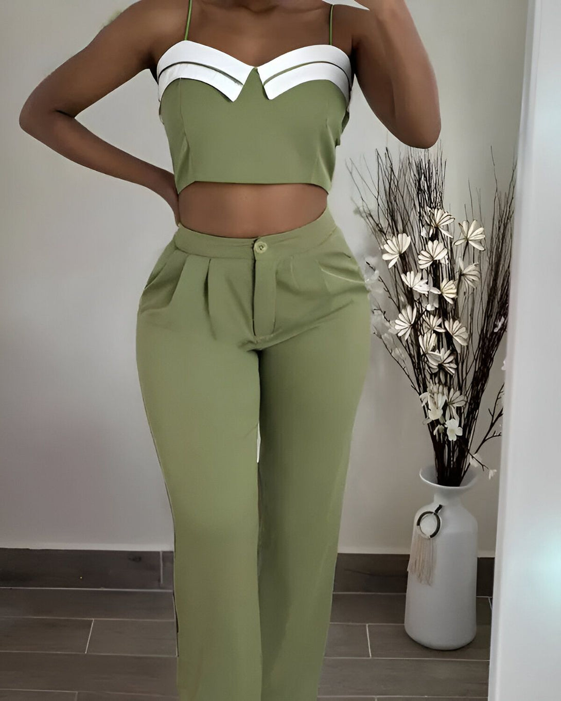 Une femme porte un ensemble pantalon et haut vert. Le haut est court et le pantalon est taille haute.