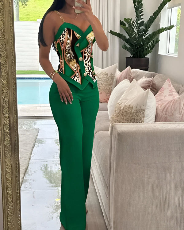 Une femme porte un pantalon vert et un haut vert à motifs avec des boutons dorés. Elle est debout dans un salon, près d'une piscine.