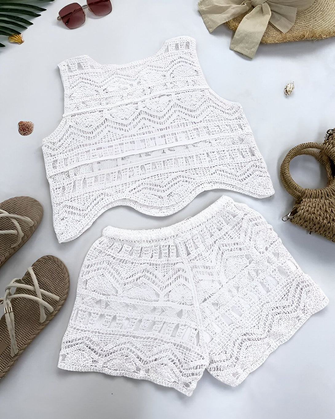 Un ensemble short et haut blanc en dentelle avec des sandales marron et un chapeau de paille beige.