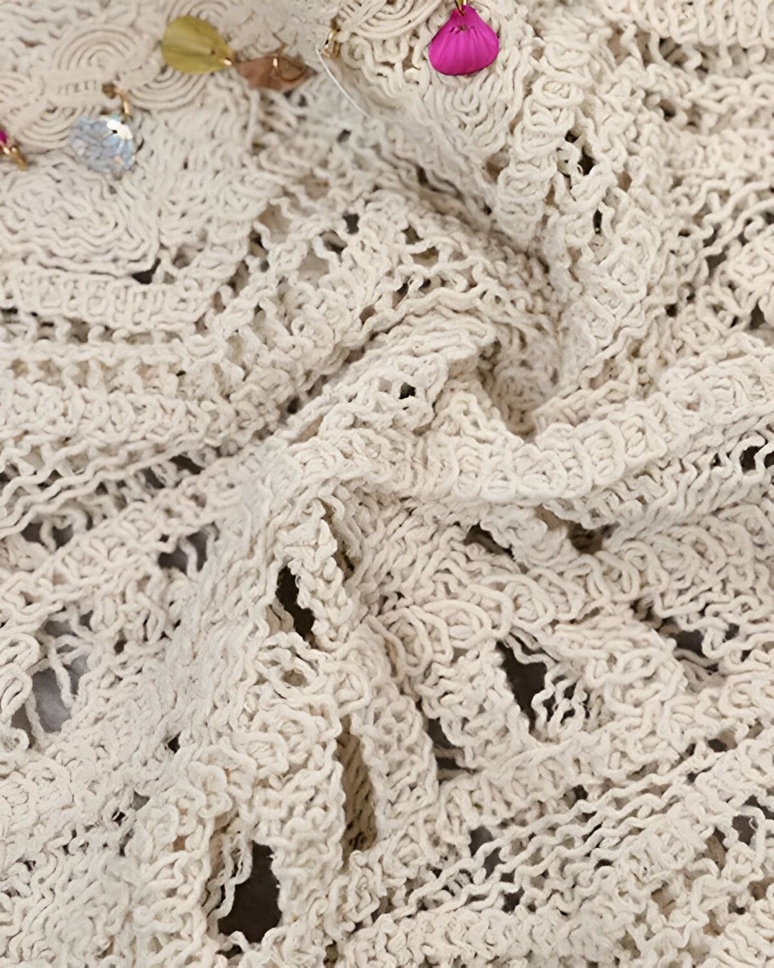 Une image de tissu beige crocheté avec des perles et des coquillages.