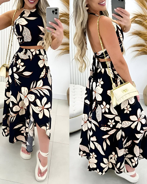 Une femme porte un ensemble deux pièces noir et blanc à motifs floraux. Le haut est un crop top à col montant et le bas est une jupe longue fendue sur le côté.