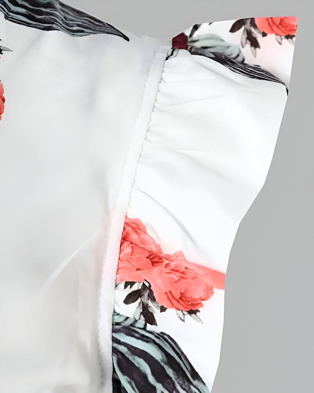 Une image d'un chemisier blanc à fleurs roses et grises. Le chemisier est porté par un mannequin. On peut voir le détail des manches bouffantes.