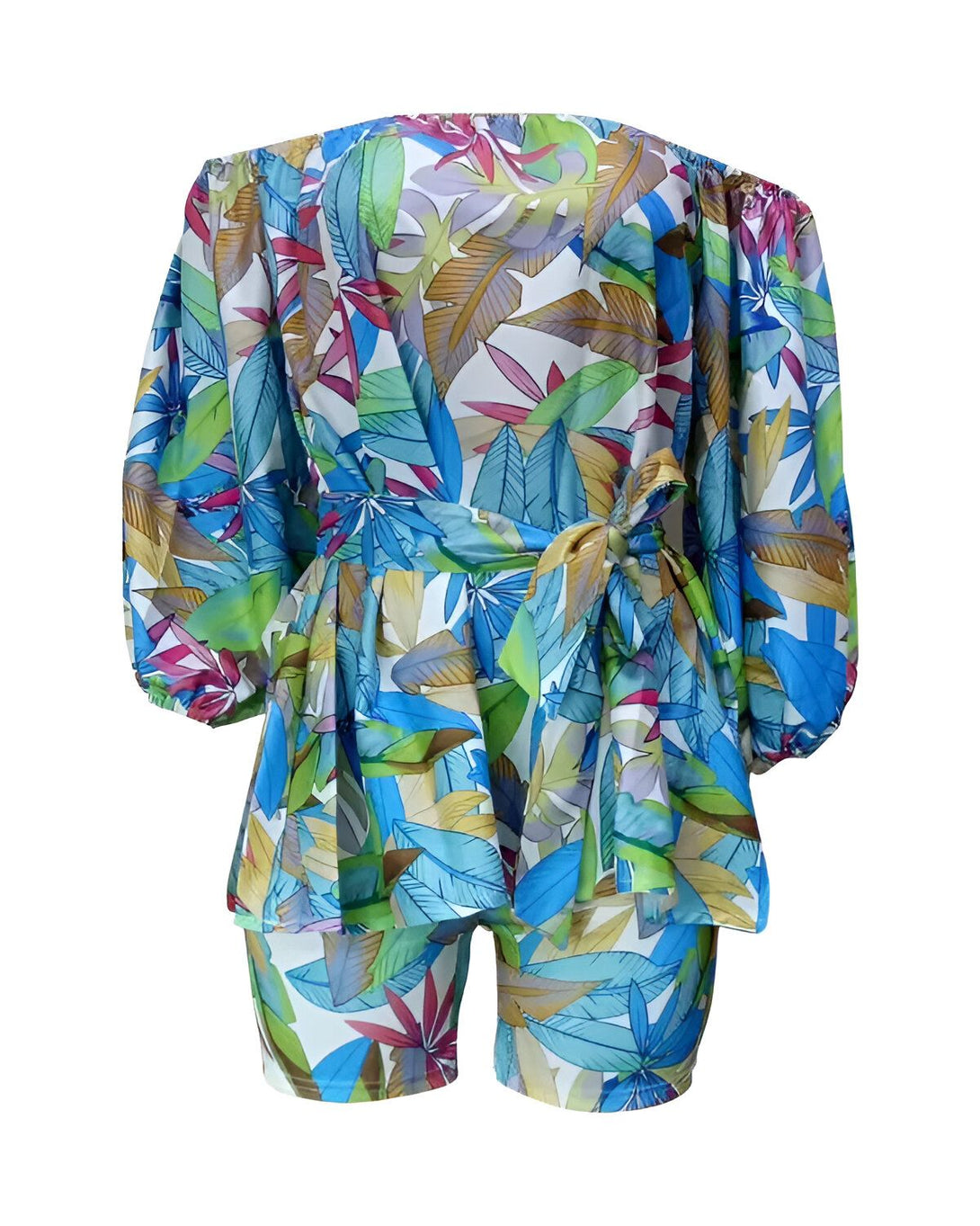 Une combinaison short et haut à imprimé tropical coloré avec des feuilles et des fleurs dans les tons de bleu, vert, jaune et rose. Le haut est à épaules dénudées et noué à la taille.