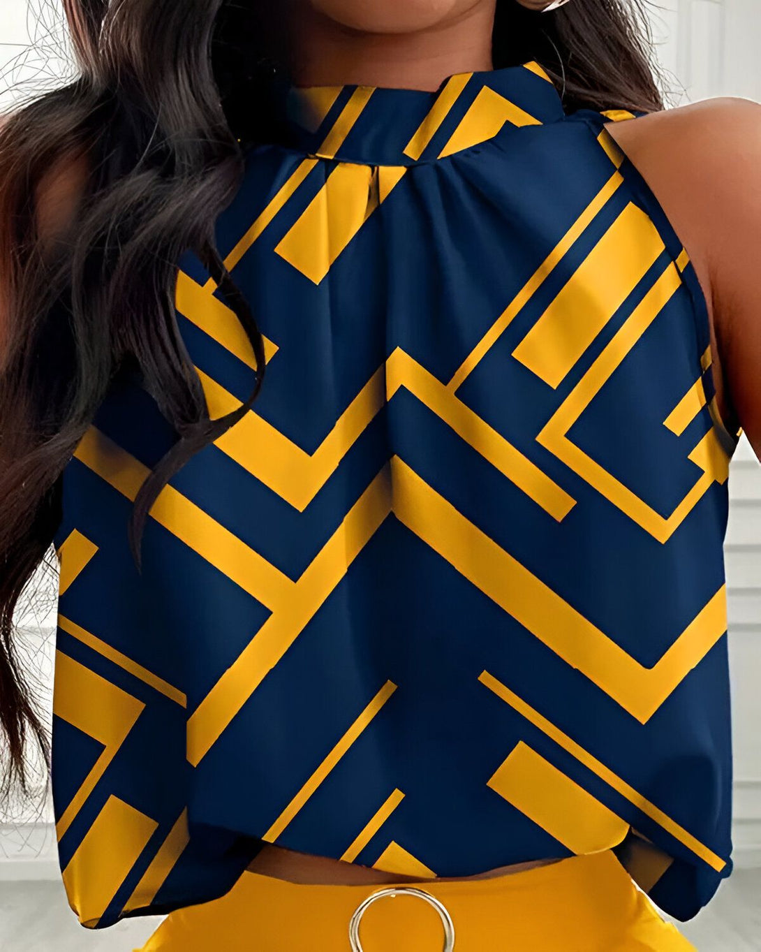Une femme porte un chemisier bleu et jaune à col montant et des motifs géométriques.