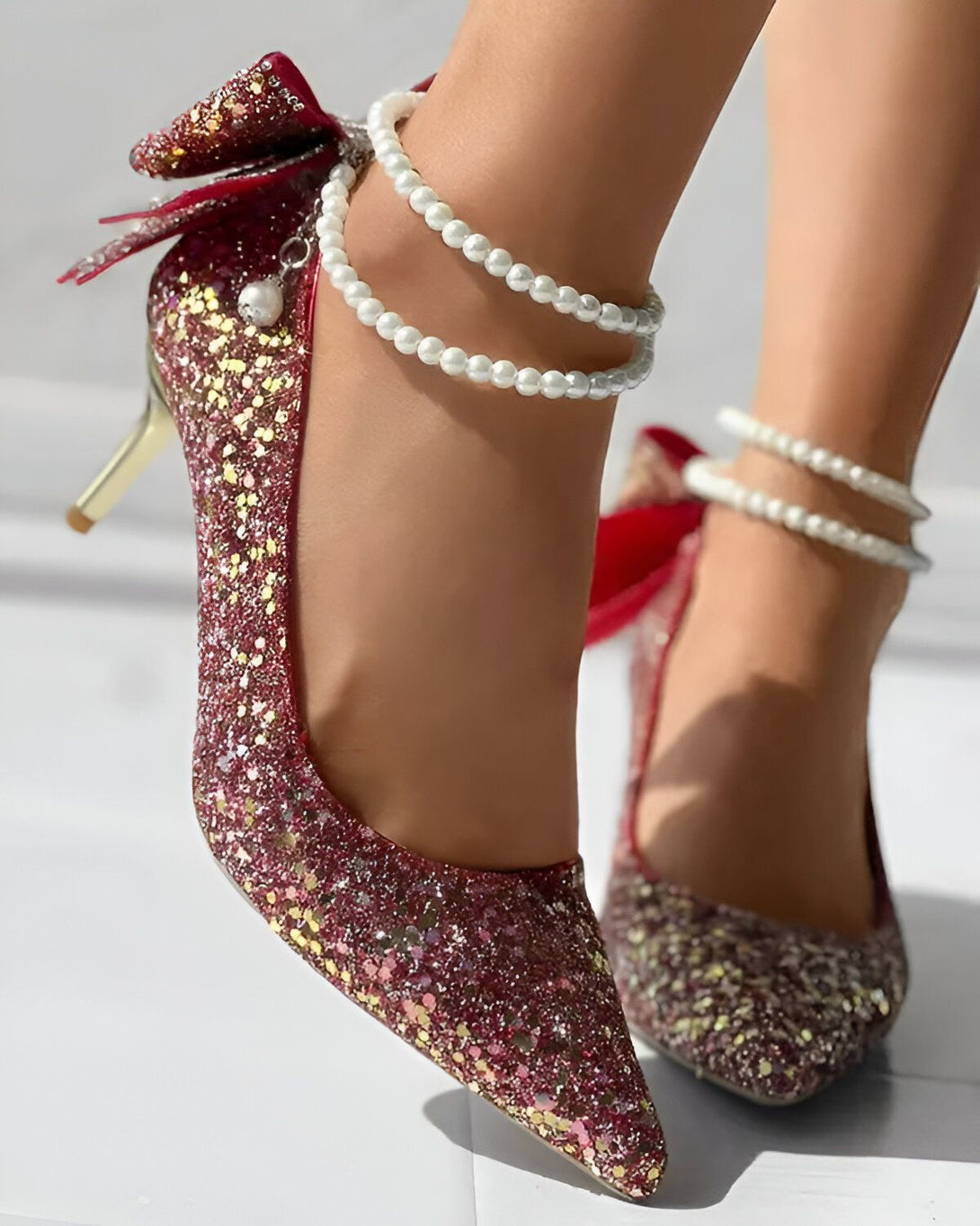 Une image de chaussures à talons rouges à paillettes avec un nœud sur le devant et des perles autour de la cheville.