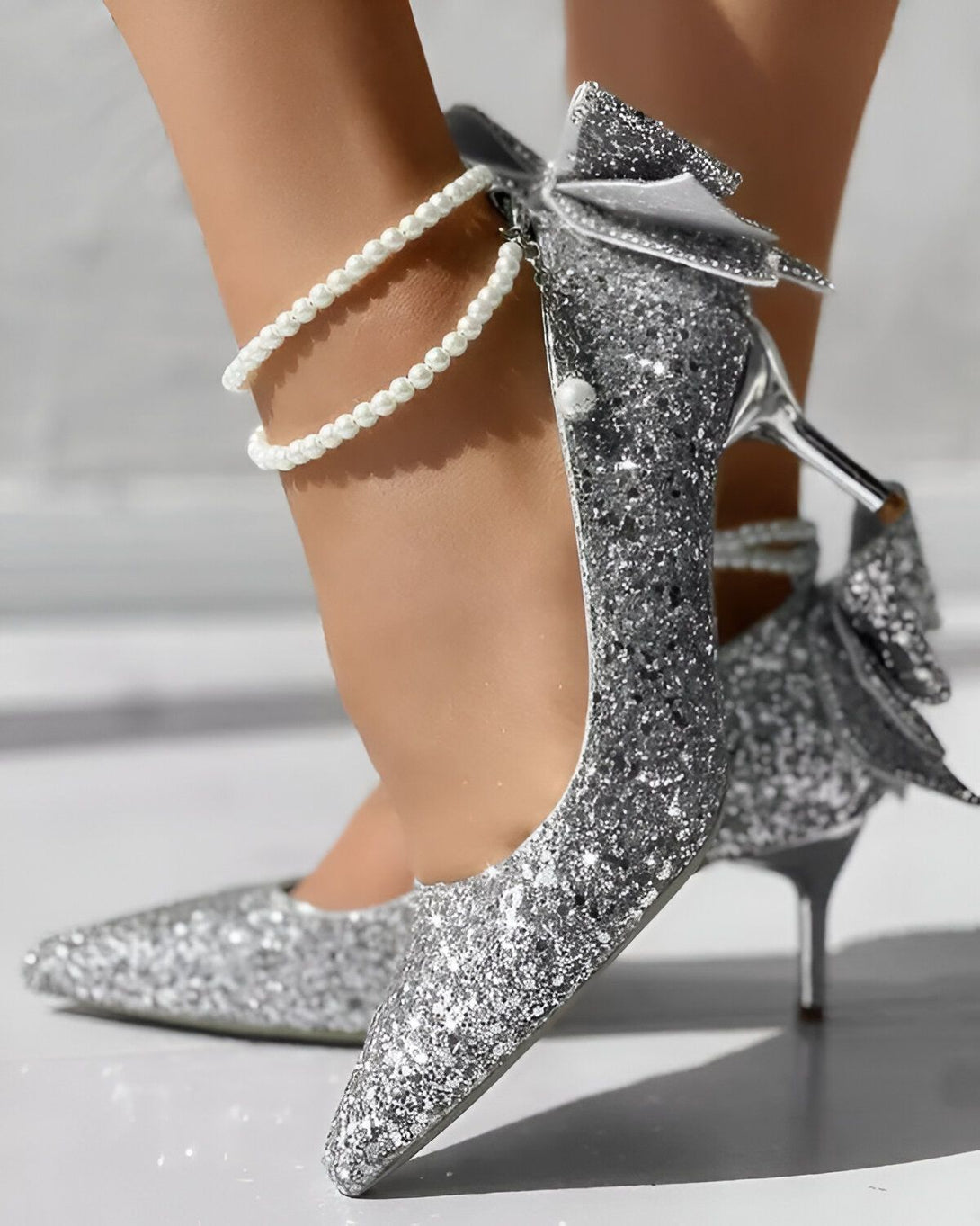 Une image d'une paire d'escarpins argentés à talons hauts avec une bride perlée autour de la cheville.
