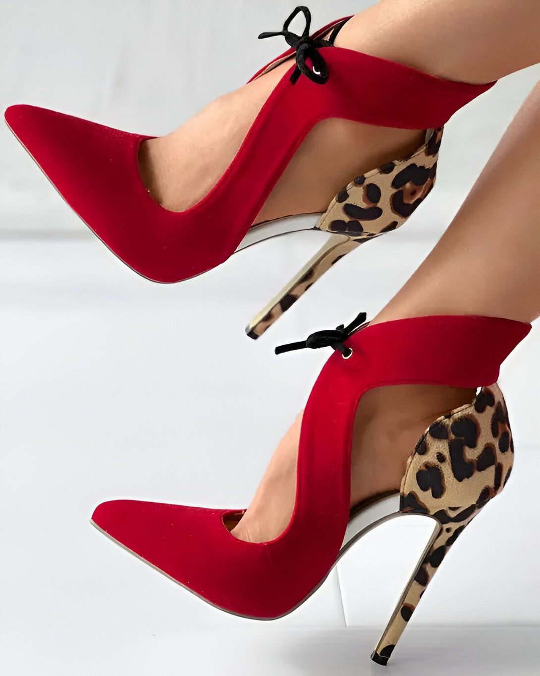 Une paire d'escarpins rouges à talons hauts avec un bout pointu et une bride à lacets autour de la cheville. L'intérieur de l'escarpin est en léopard.
