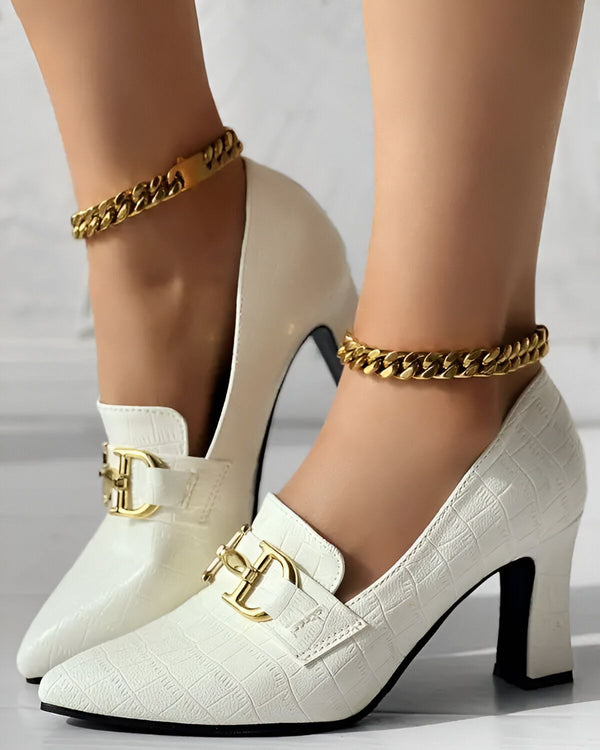 Une paire d'escarpins blancs à talons hauts avec une chaîne dorée autour de la cheville.