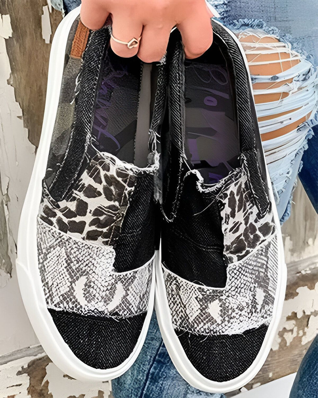 Une image de chaussures à enfiler noires et blanches avec des motifs animaliers. Les chaussures sont portées par une femme qui porte des jeans bleus déchirés.
